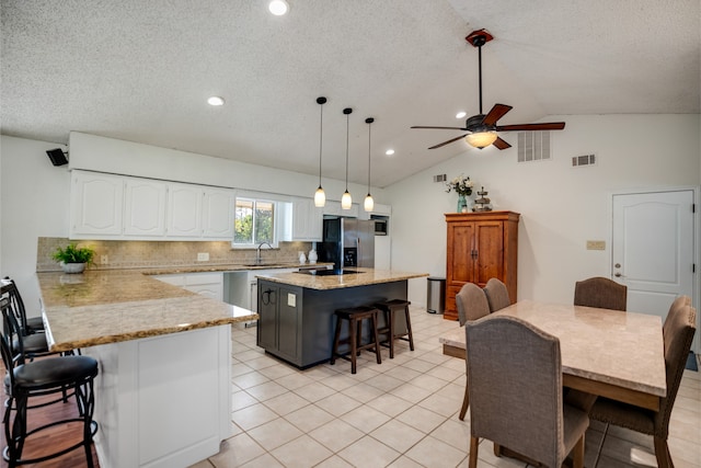 kitchen featuring pendant lighting, a center island, sink, stainless steel fridge, and a kitchen bar