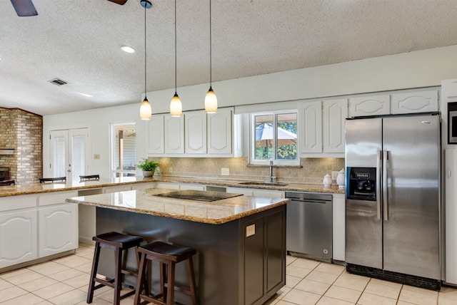 kitchen featuring white cabinetry, stainless steel appliances, backsplash, pendant lighting, and a kitchen island