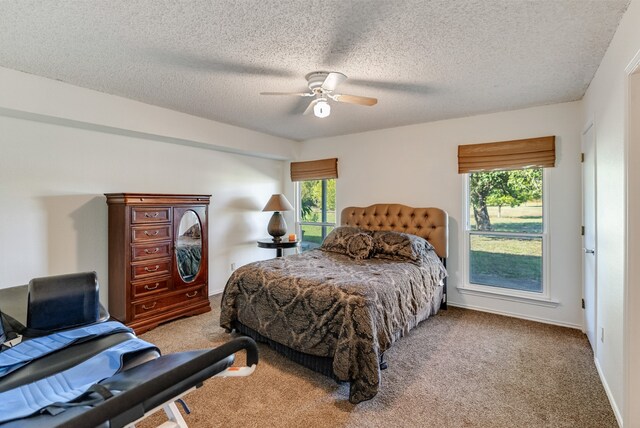 bedroom with ceiling fan, light colored carpet, a textured ceiling, and multiple windows