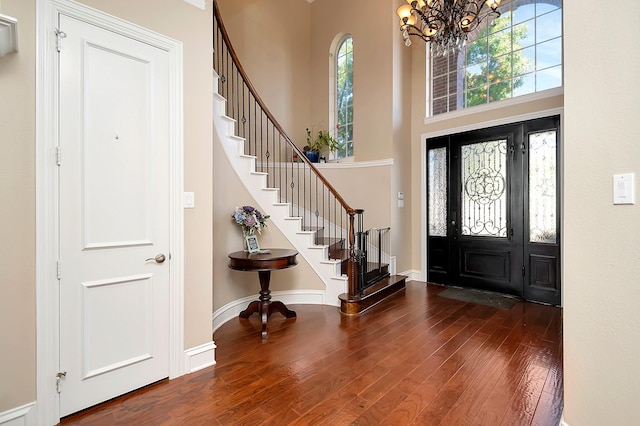 entrance foyer with a notable chandelier, a towering ceiling, and dark wood-type flooring