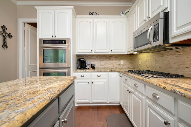 kitchen with decorative backsplash, light stone counters, white cabinets, and stainless steel appliances