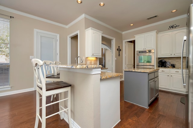 kitchen featuring light stone countertops, a center island, oven, and white cabinetry