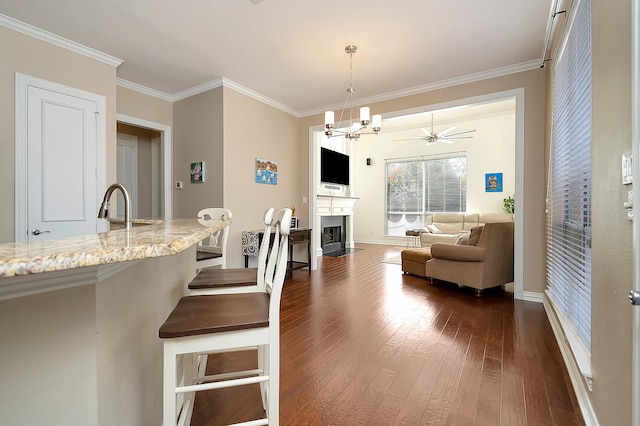 interior space with ceiling fan with notable chandelier, dark hardwood / wood-style flooring, ornamental molding, and sink