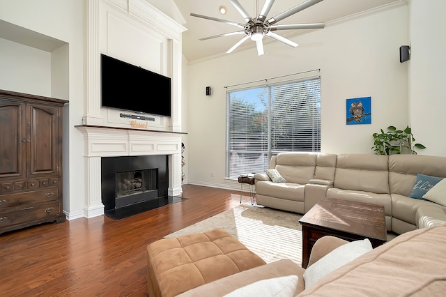 living room featuring crown molding, a large fireplace, ceiling fan, and dark wood-type flooring