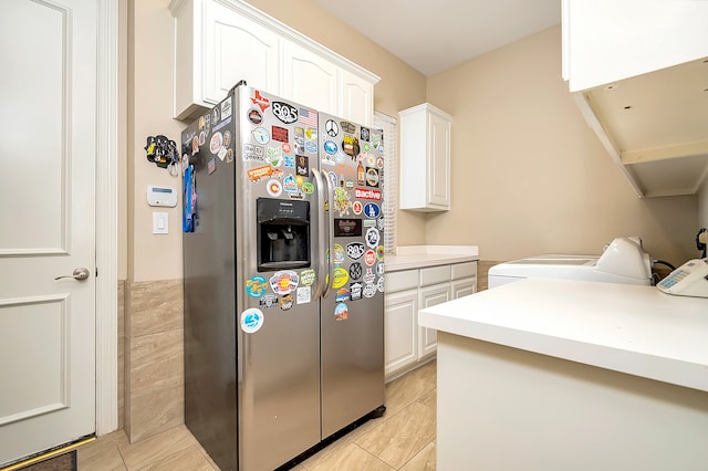 kitchen with stainless steel refrigerator with ice dispenser, light tile patterned floors, separate washer and dryer, and white cabinetry