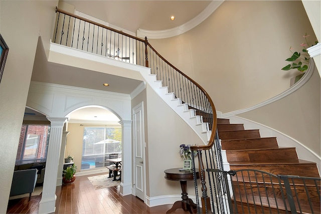 stairway featuring hardwood / wood-style floors, ornate columns, and ornamental molding