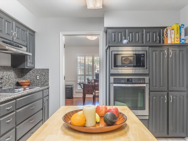 kitchen featuring decorative backsplash, appliances with stainless steel finishes, and gray cabinetry