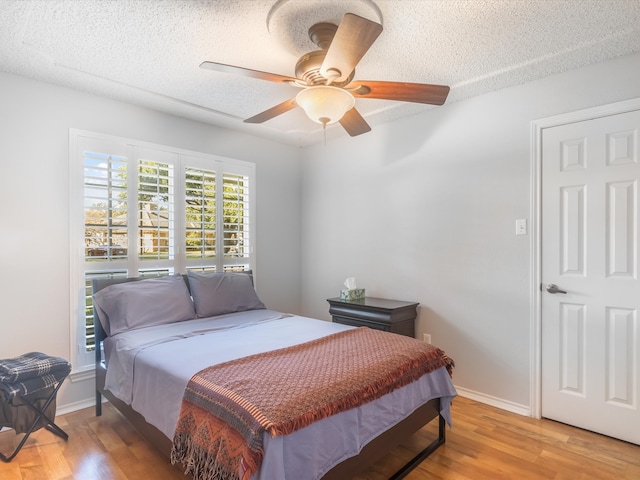 bedroom featuring wood-type flooring, a textured ceiling, and ceiling fan