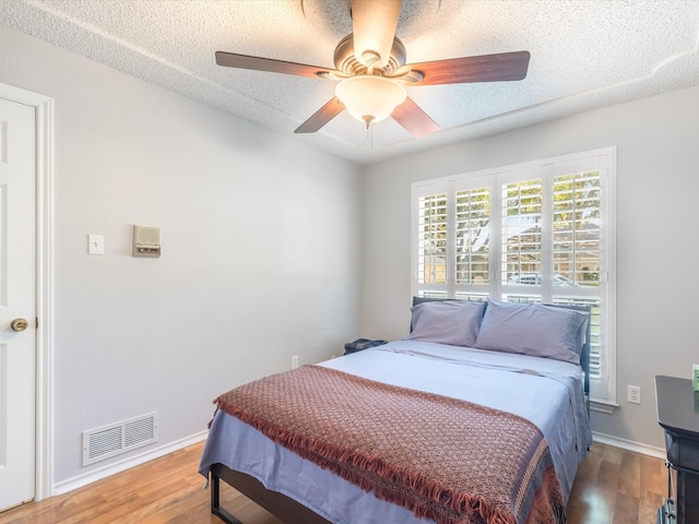 bedroom featuring ceiling fan, wood-type flooring, and a textured ceiling