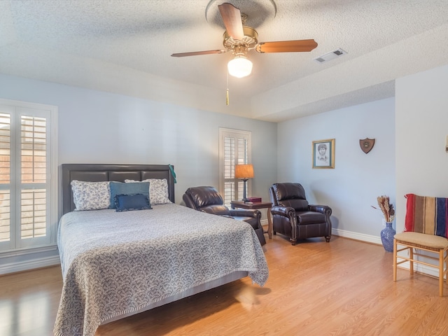 bedroom featuring ceiling fan, light hardwood / wood-style floors, and a textured ceiling