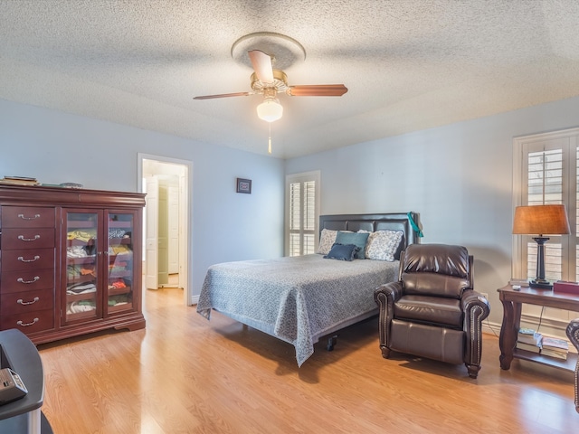 bedroom with ceiling fan, a textured ceiling, and light hardwood / wood-style flooring