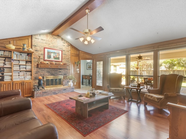 living room with vaulted ceiling with beams, wood walls, wood-type flooring, and a textured ceiling