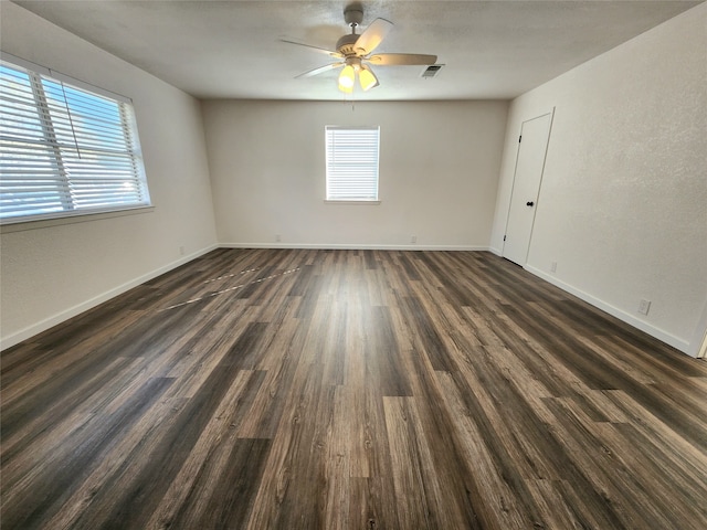 spare room featuring a wealth of natural light, dark wood-type flooring, and ceiling fan