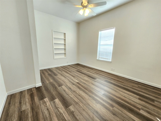 unfurnished room with built in shelves, ceiling fan, and dark wood-type flooring