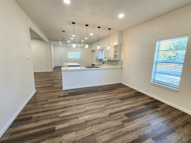 kitchen with kitchen peninsula, white cabinets, pendant lighting, and dark hardwood / wood-style floors