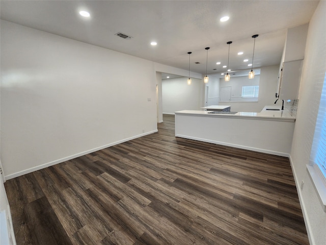 kitchen with decorative light fixtures, dark hardwood / wood-style flooring, kitchen peninsula, and sink