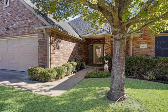 doorway to property with a garage and a yard