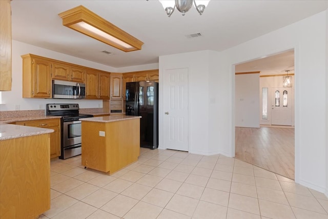 kitchen with a notable chandelier, a center island, light tile patterned floors, and stainless steel appliances