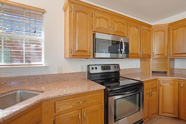 kitchen with light stone countertops, stainless steel appliances, and light tile patterned flooring