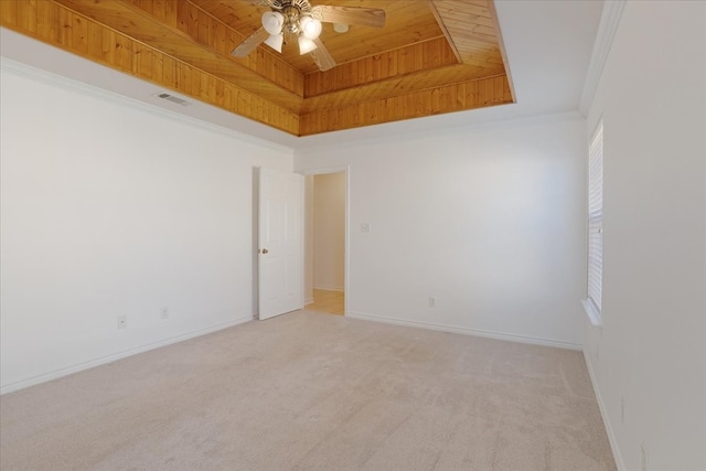 empty room with ceiling fan, a raised ceiling, light colored carpet, and crown molding