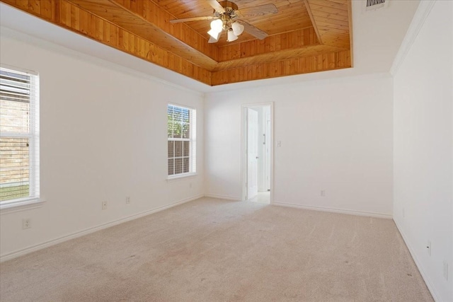 carpeted spare room with ornamental molding, wooden ceiling, ceiling fan, and a tray ceiling