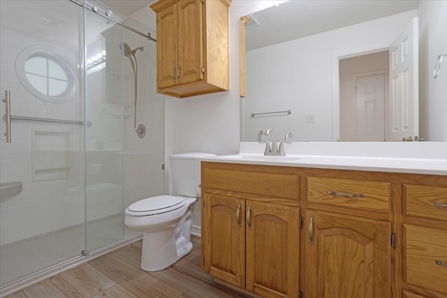 bathroom with hardwood / wood-style floors, vanity, toilet, and a shower with door