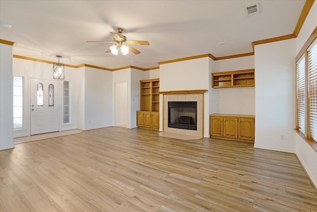 unfurnished living room with light wood-type flooring, ceiling fan, ornamental molding, and a tiled fireplace