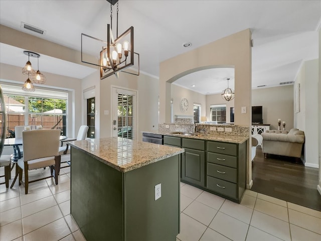 kitchen with pendant lighting, light stone counters, green cabinetry, and light tile patterned flooring