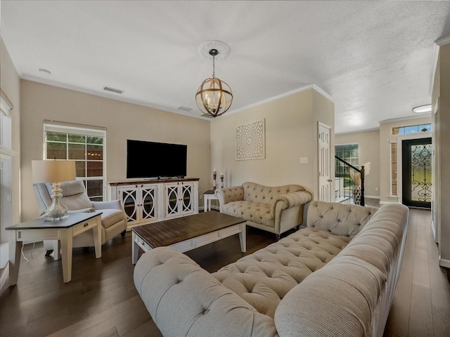 living room with ornamental molding, dark hardwood / wood-style floors, a wealth of natural light, and a notable chandelier