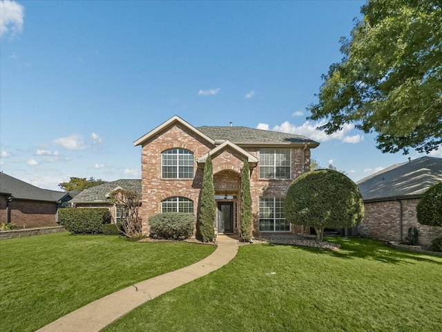 traditional home featuring brick siding, a front lawn, and roof with shingles