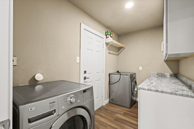 washroom with dark hardwood / wood-style flooring, cabinets, and washing machine and clothes dryer