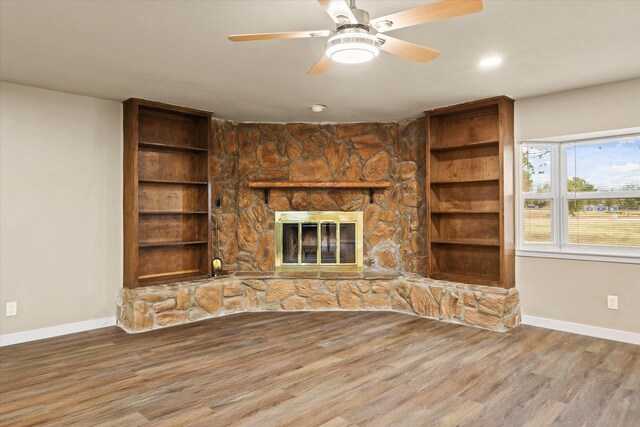 unfurnished living room with a stone fireplace, ceiling fan, and hardwood / wood-style flooring