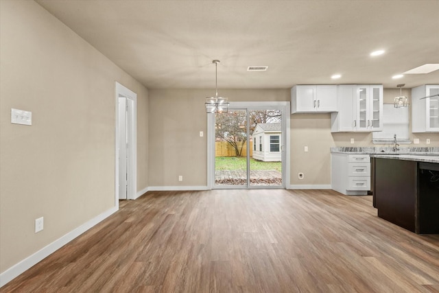 kitchen with white cabinets, pendant lighting, and light hardwood / wood-style floors