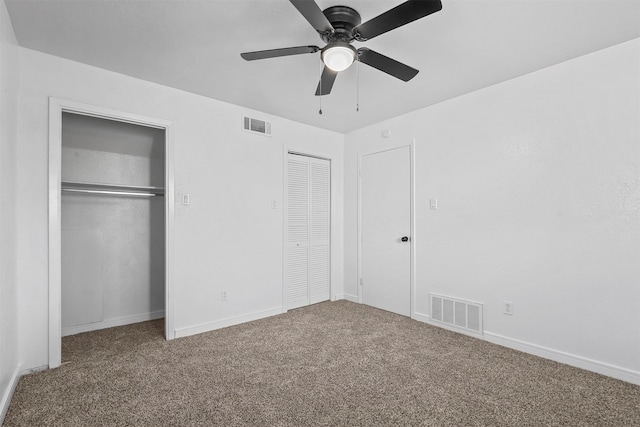 unfurnished bedroom featuring carpet flooring, ceiling fan, and multiple closets