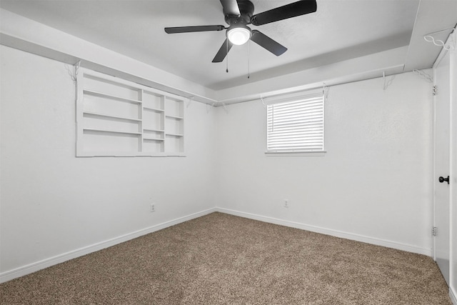 spare room with built in shelves, carpet floors, and ceiling fan