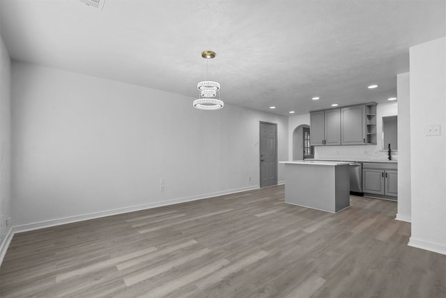 kitchen with pendant lighting, gray cabinets, a kitchen island, and hardwood / wood-style flooring