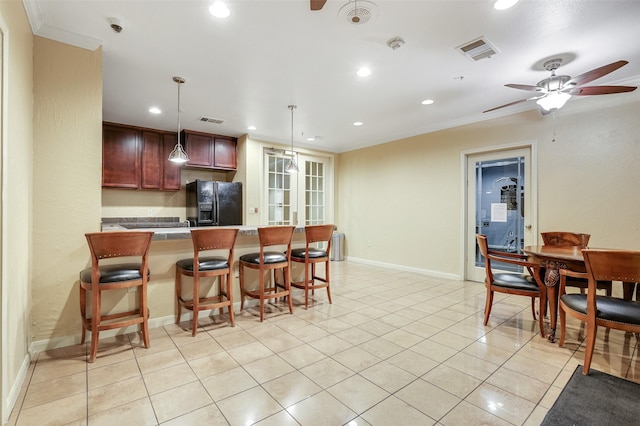 kitchen with pendant lighting, ceiling fan, ornamental molding, light tile patterned floors, and black fridge with ice dispenser