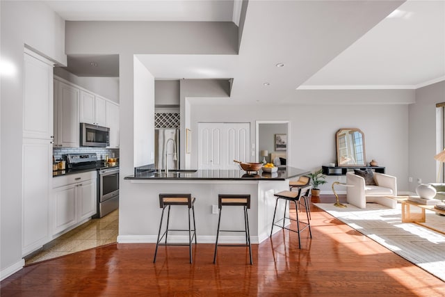 kitchen with white cabinetry, sink, a kitchen breakfast bar, decorative backsplash, and appliances with stainless steel finishes