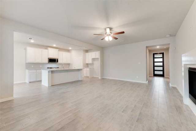 unfurnished living room featuring ceiling fan and light hardwood / wood-style floors