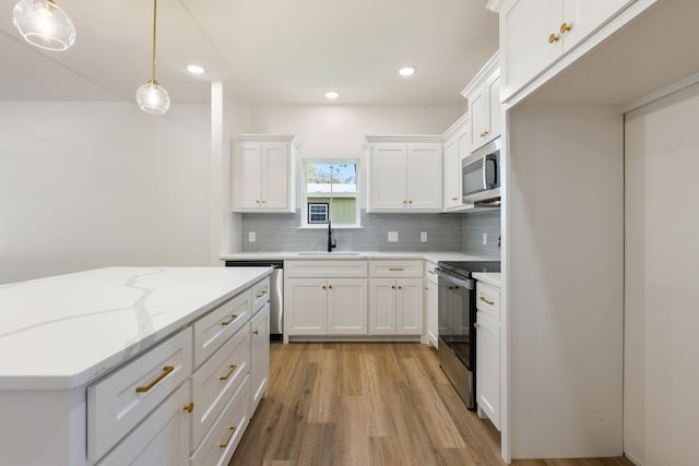 kitchen featuring white cabinetry, hanging light fixtures, stainless steel appliances, and sink