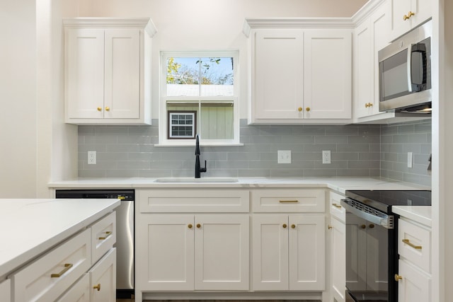 kitchen with white cabinets, appliances with stainless steel finishes, tasteful backsplash, and sink