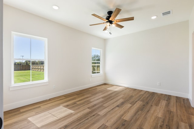 spare room with ceiling fan, a healthy amount of sunlight, and hardwood / wood-style flooring