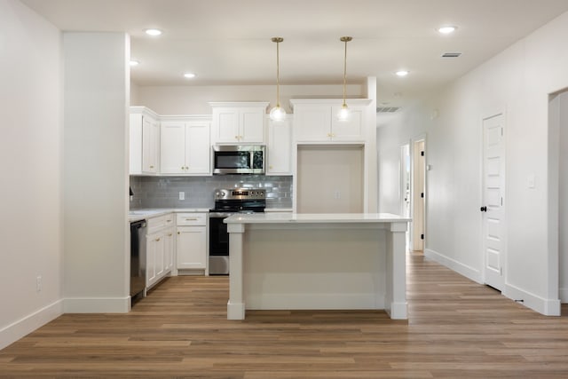 kitchen with white cabinets, a kitchen island, appliances with stainless steel finishes, and light hardwood / wood-style flooring