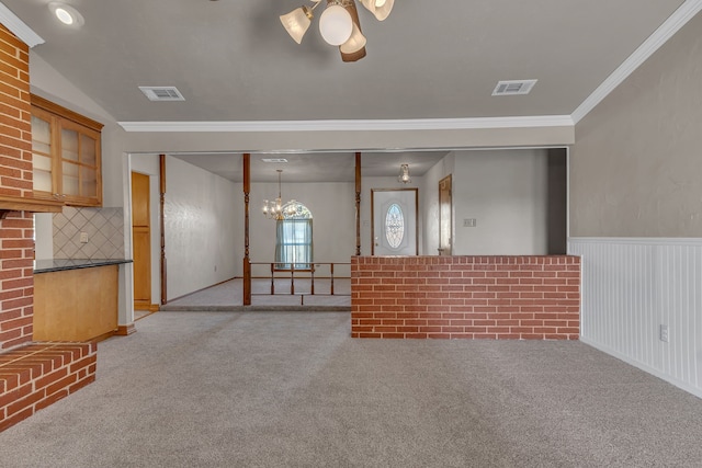 unfurnished living room with light carpet, ornamental molding, and a notable chandelier