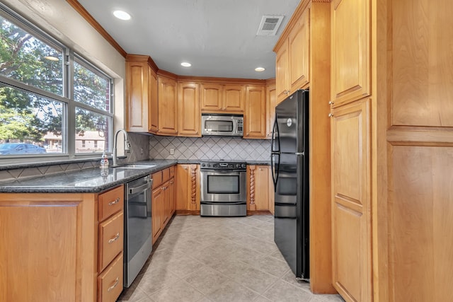 kitchen featuring sink, stainless steel appliances, backsplash, crown molding, and dark stone counters