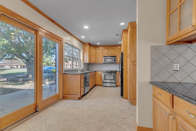 kitchen with dark stone counters, sink, decorative backsplash, ornamental molding, and appliances with stainless steel finishes