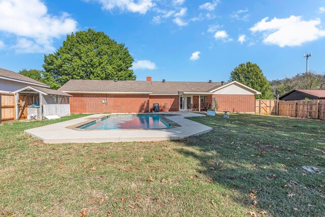 rear view of house featuring a fenced in pool, a patio area, and a lawn