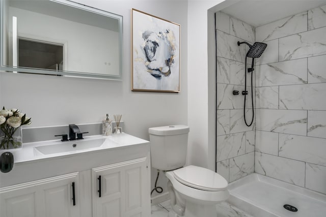 bathroom with a tile shower, vanity, and toilet