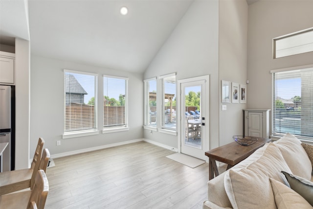 living room featuring light hardwood / wood-style floors, high vaulted ceiling, and a healthy amount of sunlight