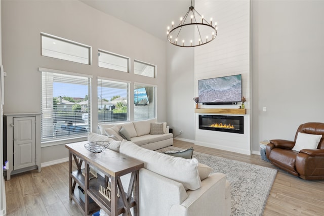 living room with a towering ceiling, light hardwood / wood-style flooring, and a notable chandelier